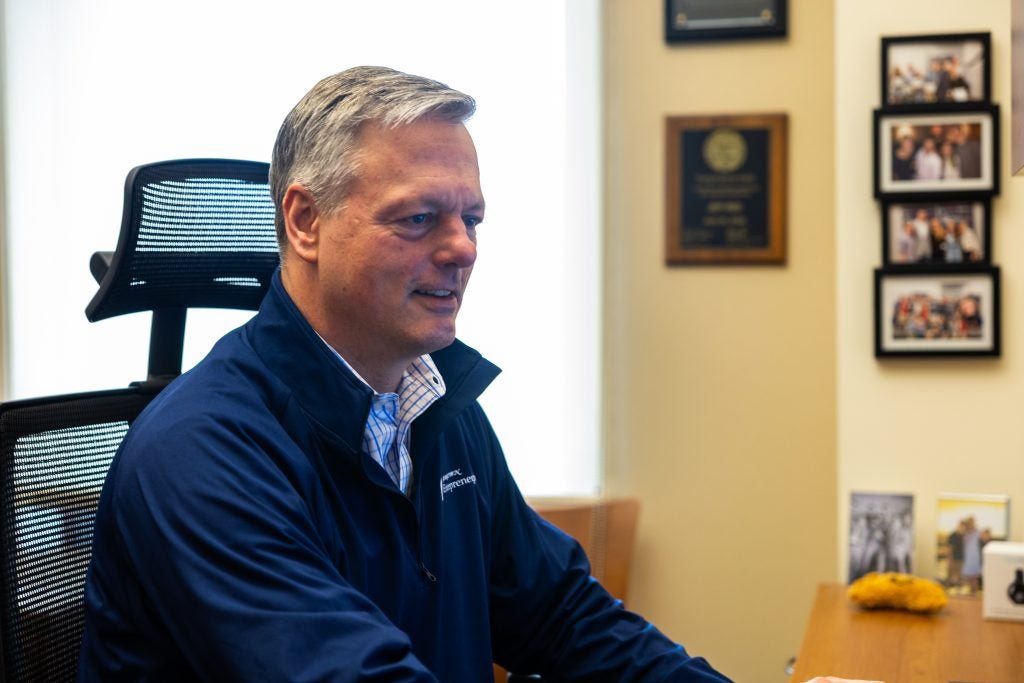 A man smiles while typing at his desk