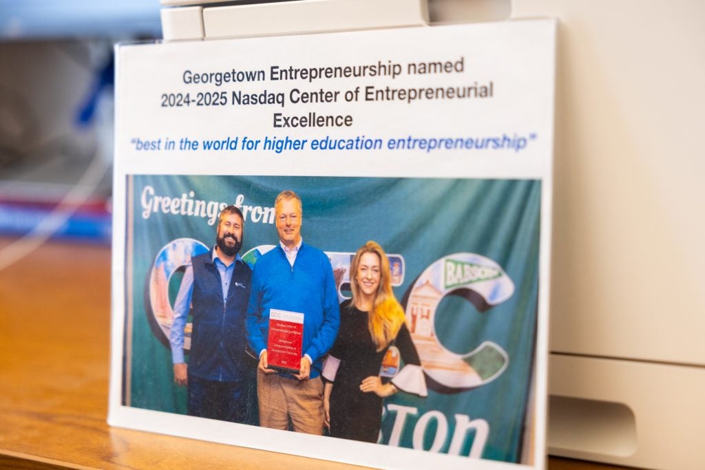 An award with writing and a photo of three people holding a trophy