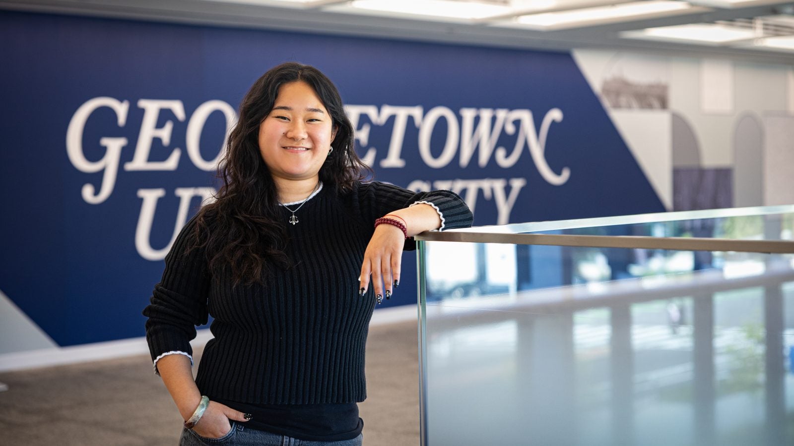 Portrait of Andrea in a GU building leaning on a railing