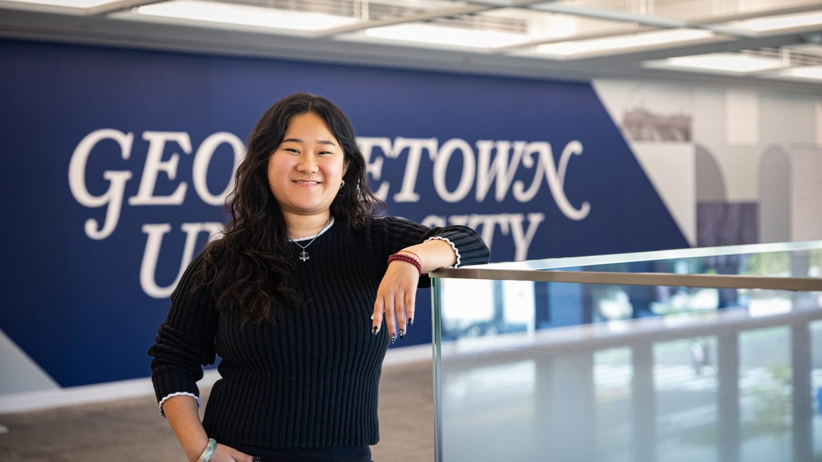 Portrait of Andrea in a GU building leaning on a railing