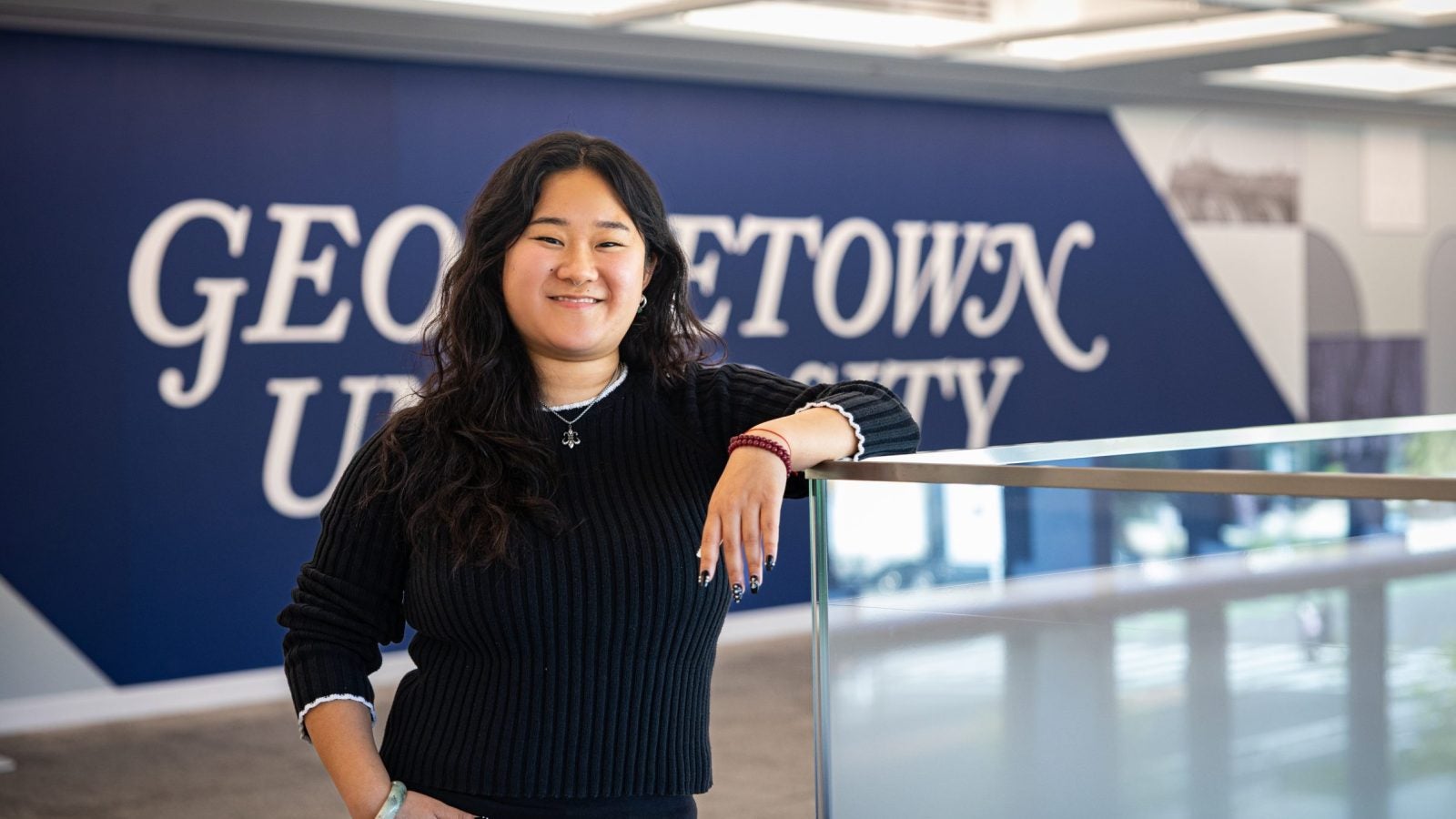 Portrait of Andrea in a GU building leaning on a railing
