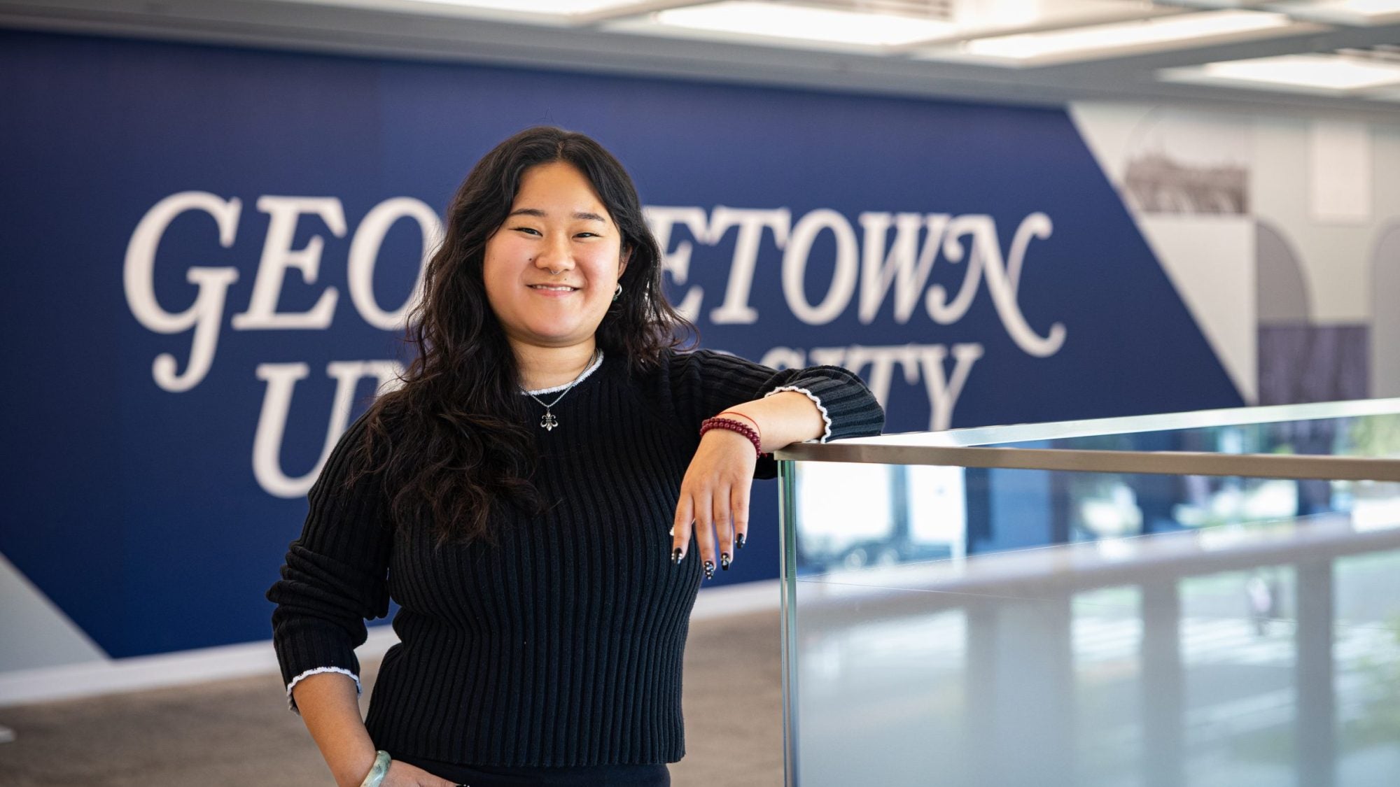 Portrait of Andrea in a GU building leaning on a railing