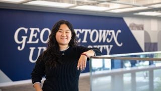 Portrait of Andrea in a GU building leaning on a railing