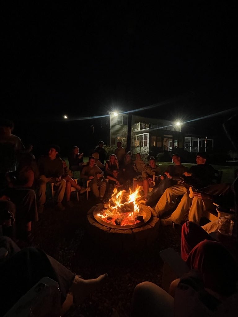 Group of young people around a bonfire in a backyard at night