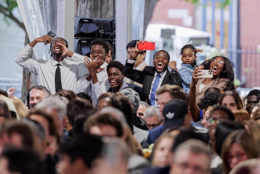 A group of people cheer and hold up cell phones in a crowd