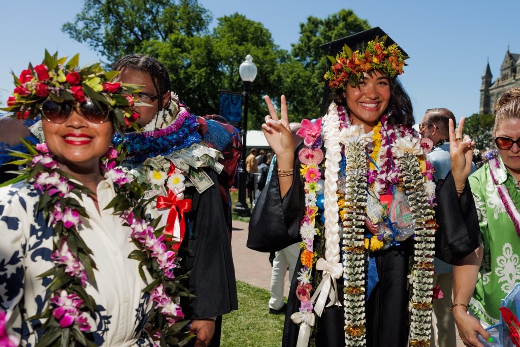 Two women dressed in colorful flowers smile