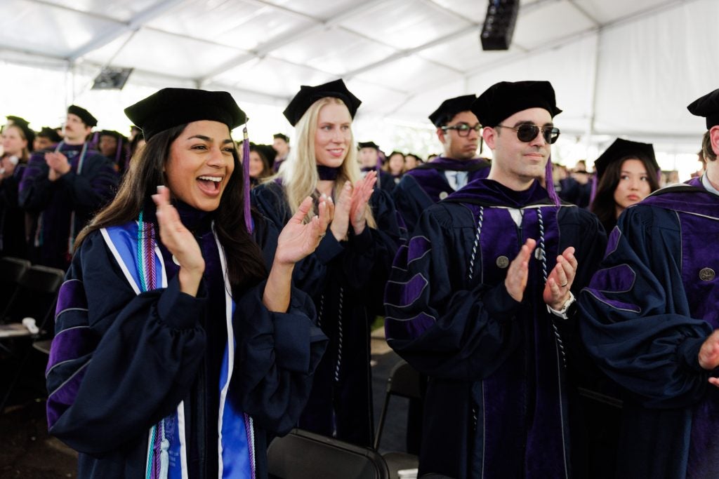 Law students cheer and clap while wearing cap and gowns