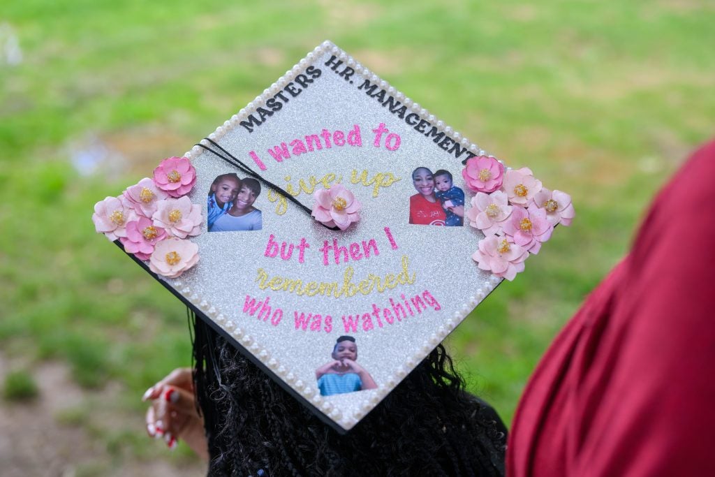 A close-up of a graduation cap that says, "Masters H.R. Management...I wanted to give up but then I remembered who was watching" with photos of her child. 