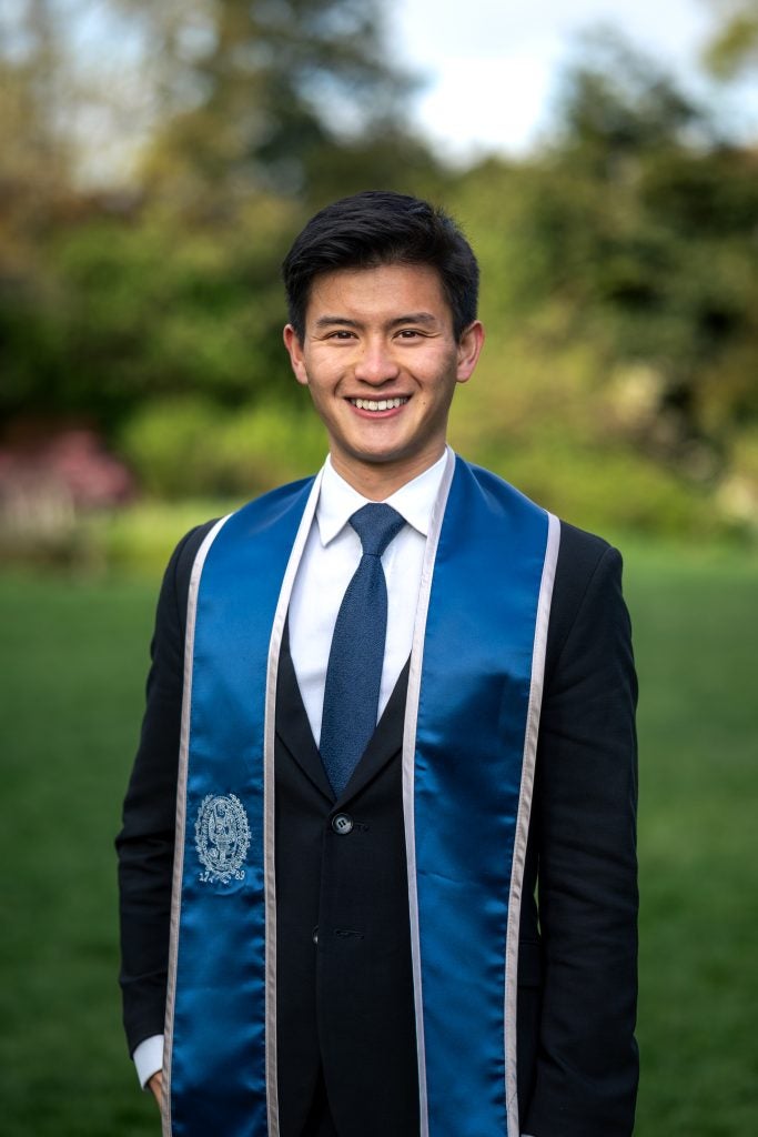 Young Asian man in a suit and tie with a blue graduation stole