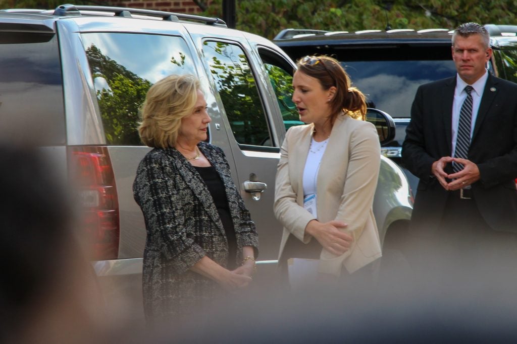 Two women speak outside next to a car