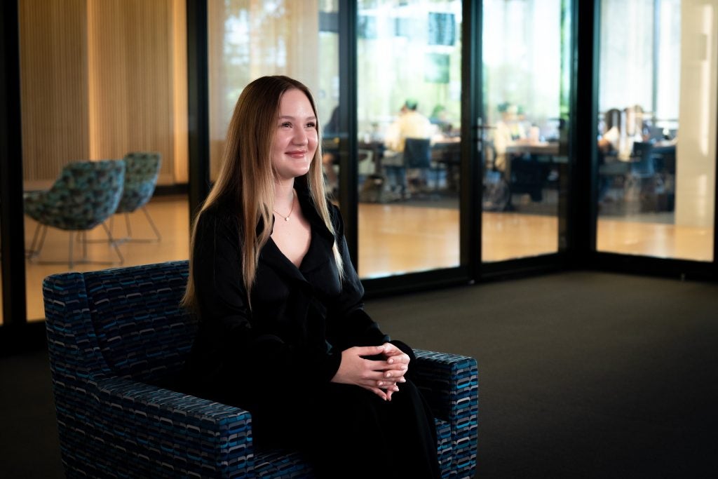Young Ukrainian woman smiling while sitting in chair watching a big screen