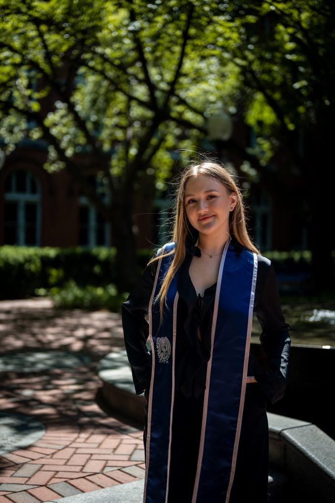 Young Caucasian woman in graduation regalia smiling