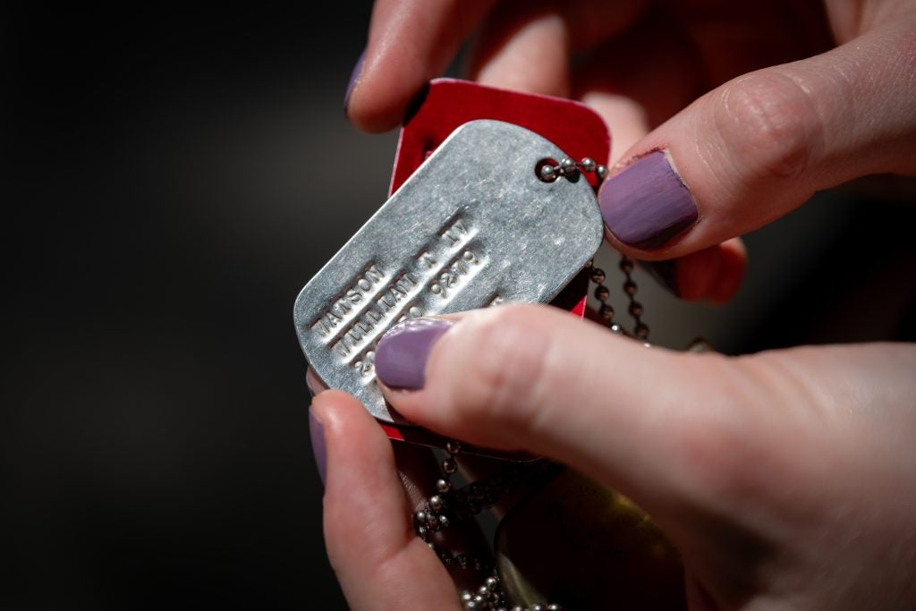 Dog tags on a chain with hands holding them