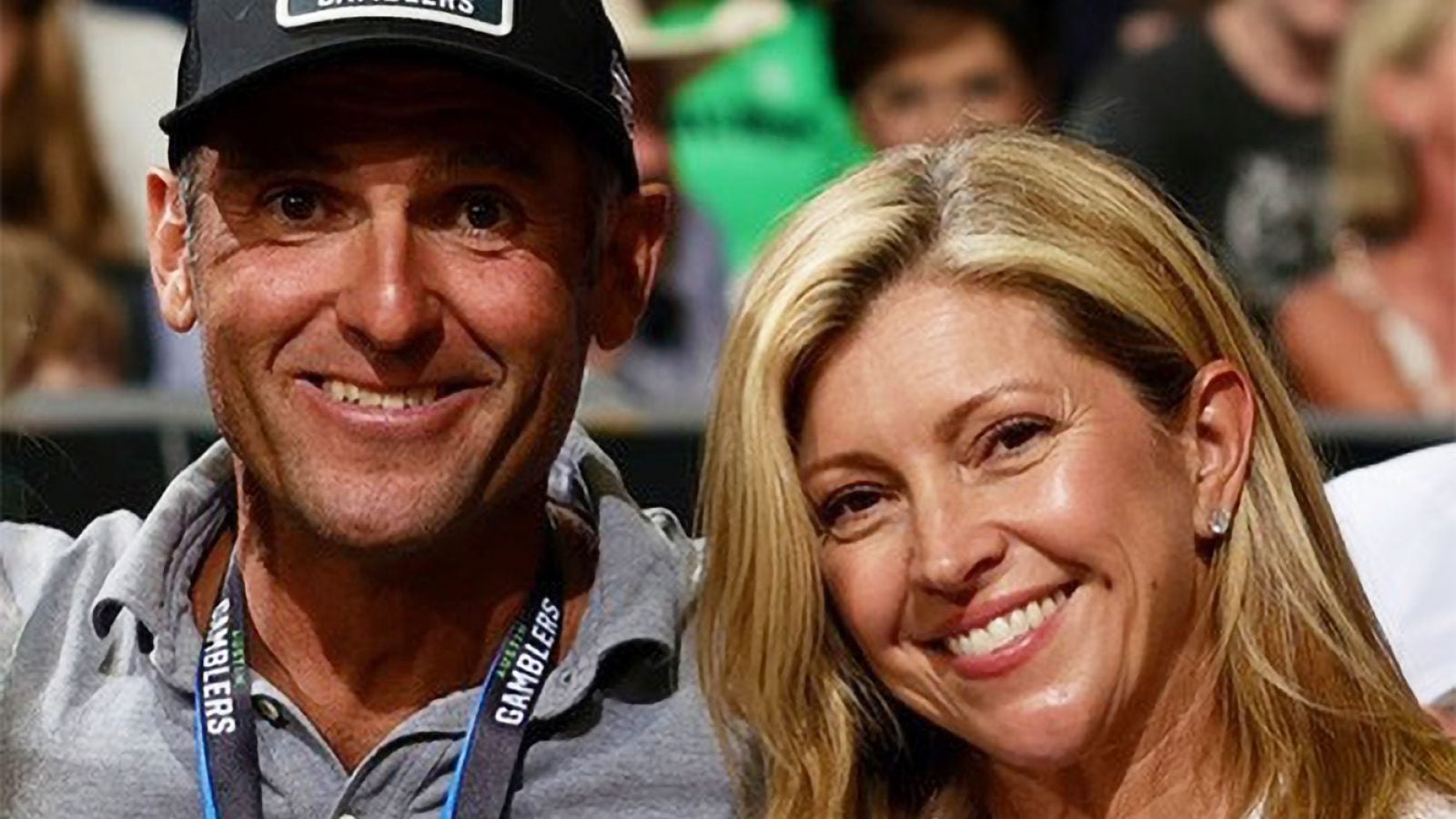 A husband and wife smile at a sports game