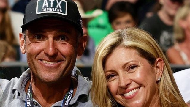 A husband and wife smile at a sports game