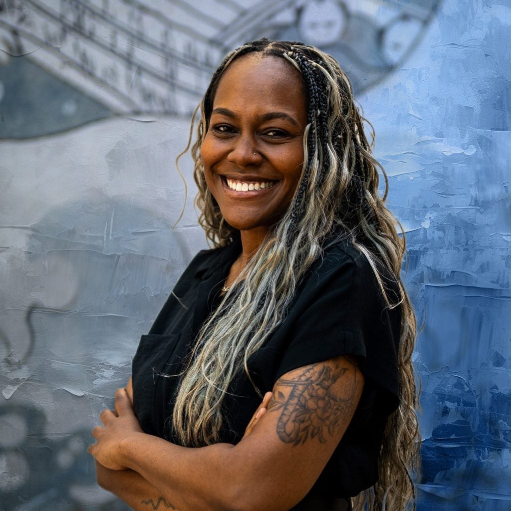 Black woman with arms crossed wearing a black shirt