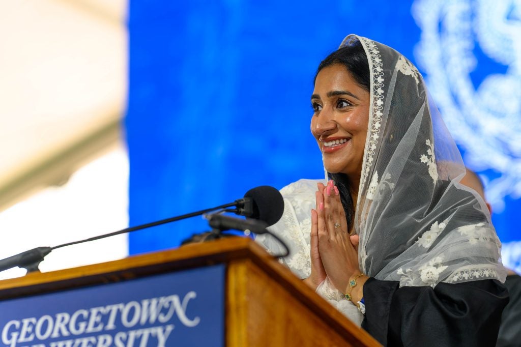 A student prays while standing behind a podium 