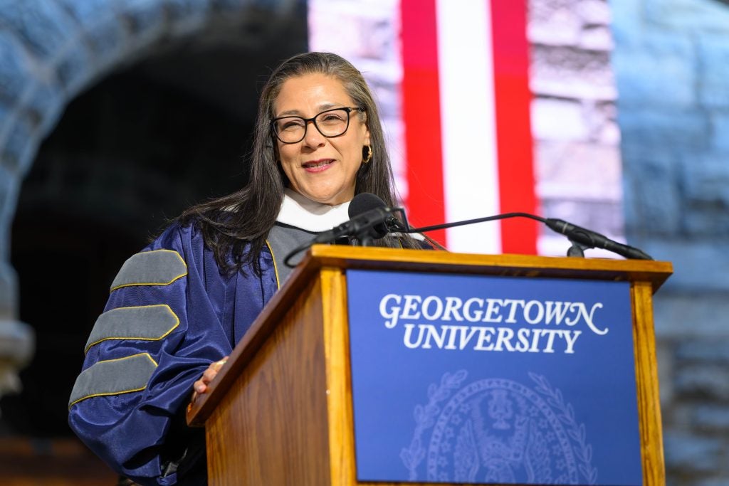 Woman with glasses speaking at a podium