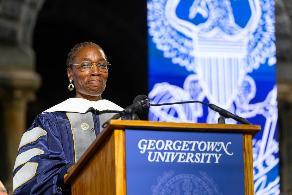 Black woman with glasses speaking at a podium at Georgetown commencement