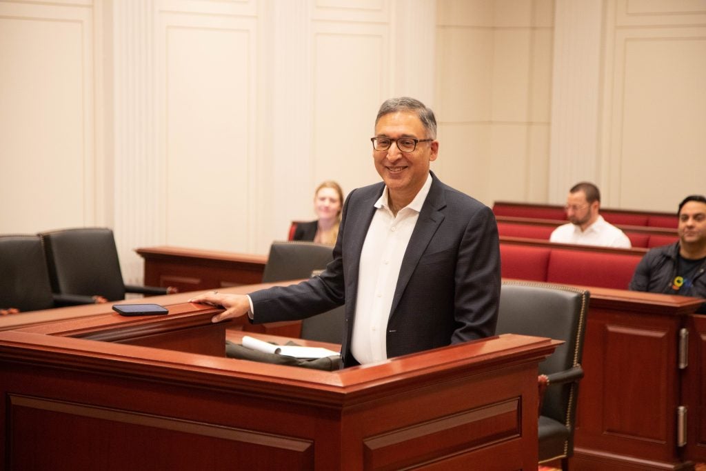 Man with glasses in suit at a podium in a moot court room