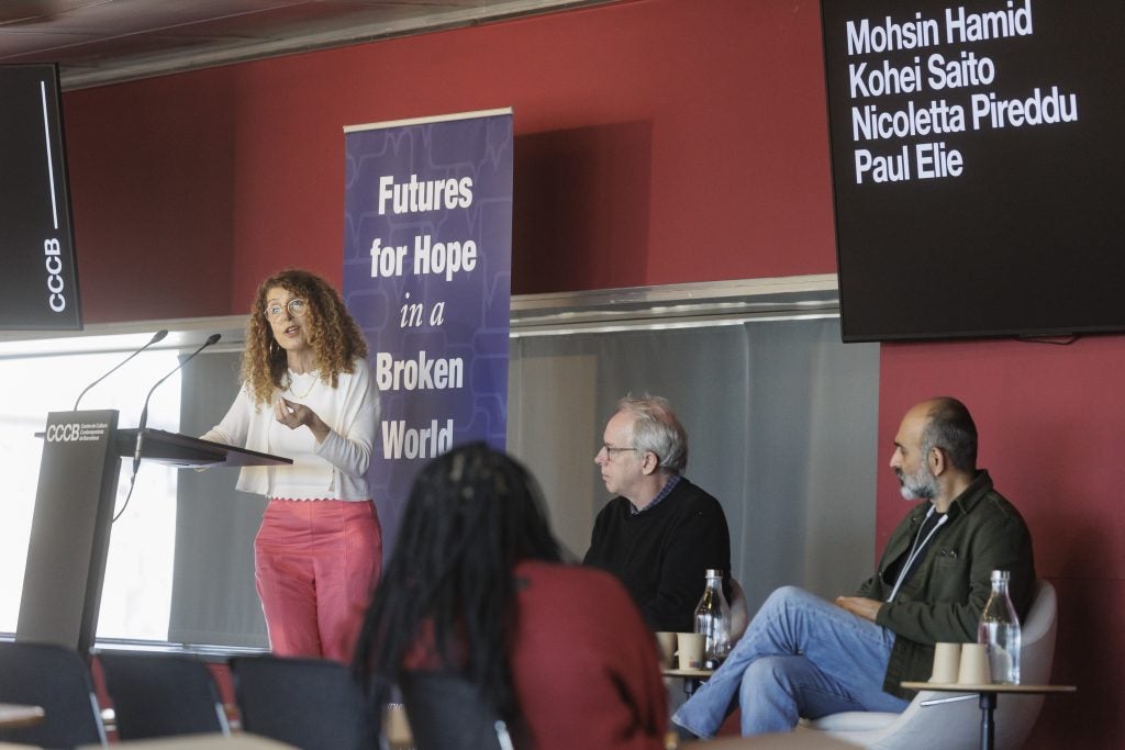 Woman presenting at a podium as part of a panel