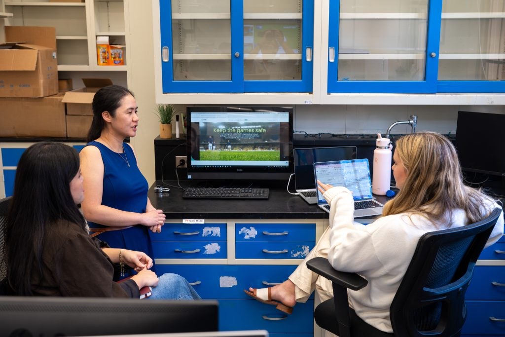 Three people at a lab bench talking together