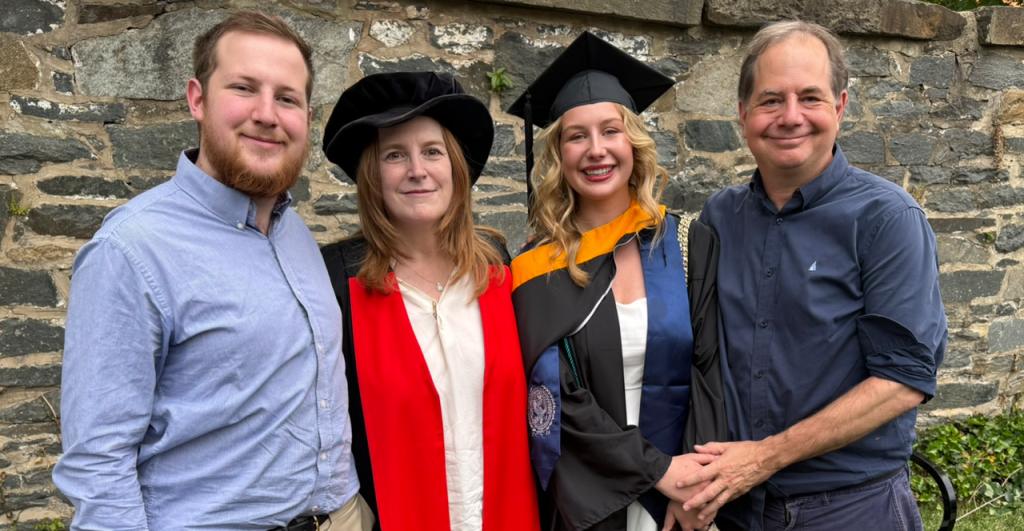 Two young adults with their parents. The mother and daughter in graduation regalia