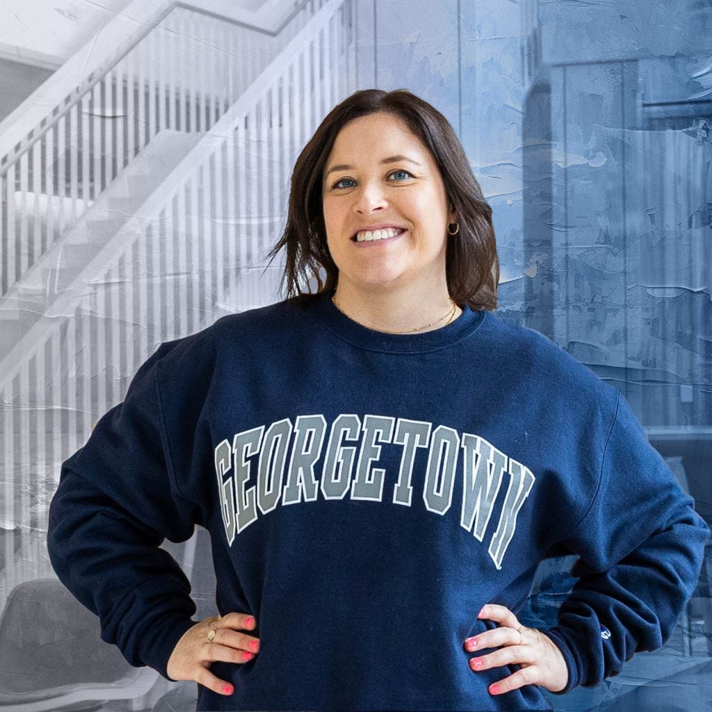 Woman smiling with hands on hips in a GU sweatshirt