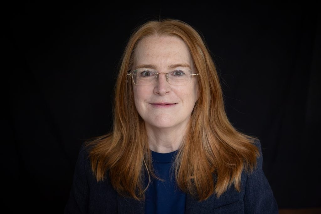 Headshot of woman with glasses against a black background