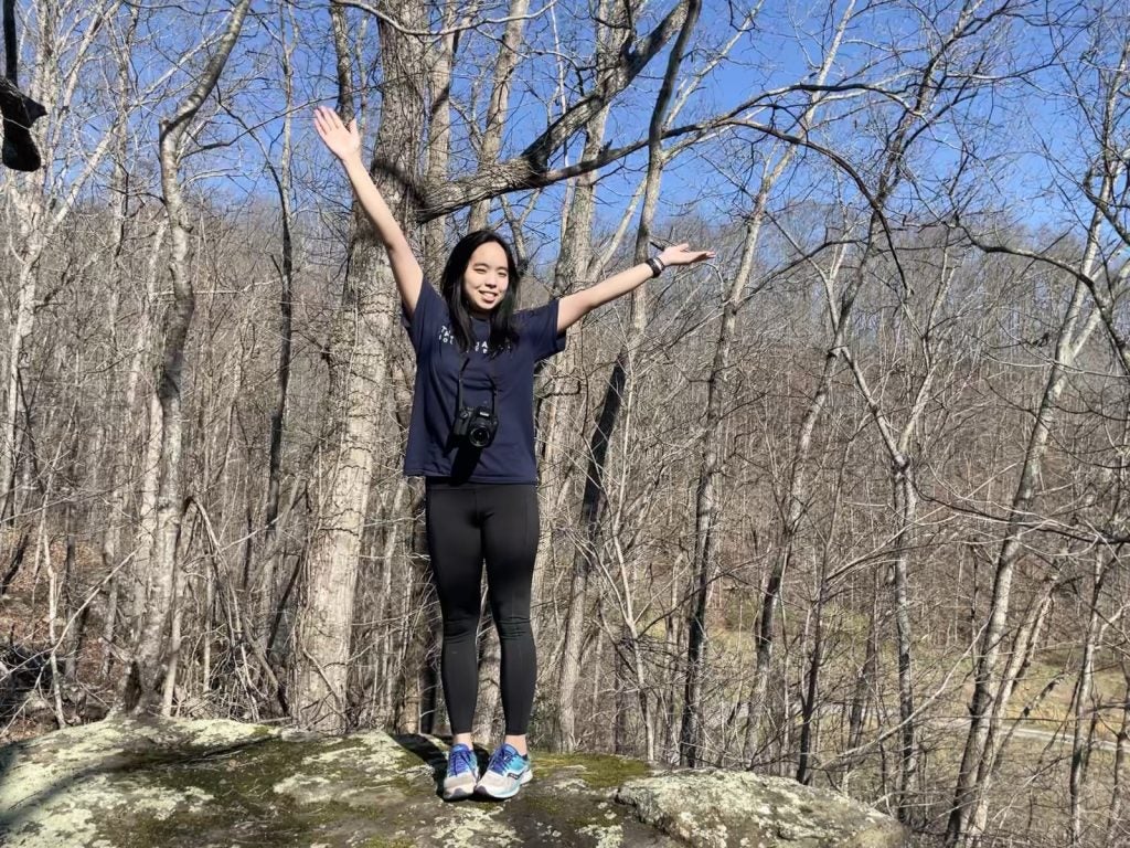 Young Asian woman in blue t shirt smiling with arms raised