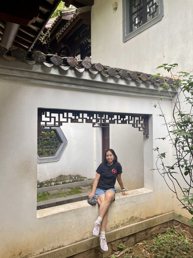 Young Asian woman sitting on a window sill smiling