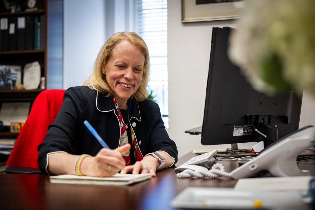 A woman writes on a pad of paper at a desk