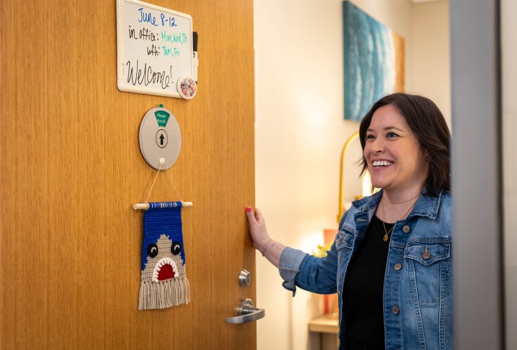 A woman smiles as she opens her office door