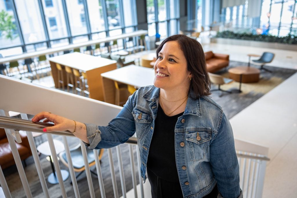 A woman in a jean jacket smiles as she climbs up a staircase