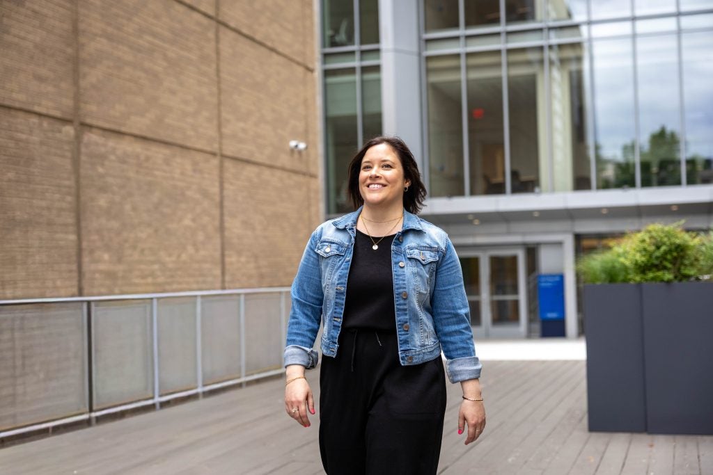 A woman smiles as she walks outside a building