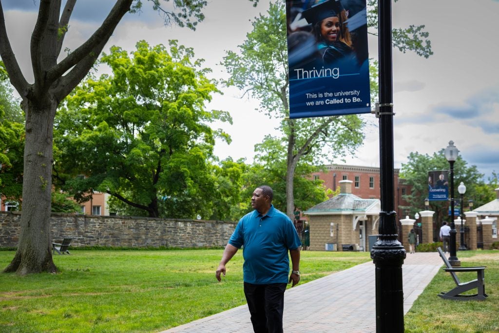 Black man in blue shirt walking on a clear day