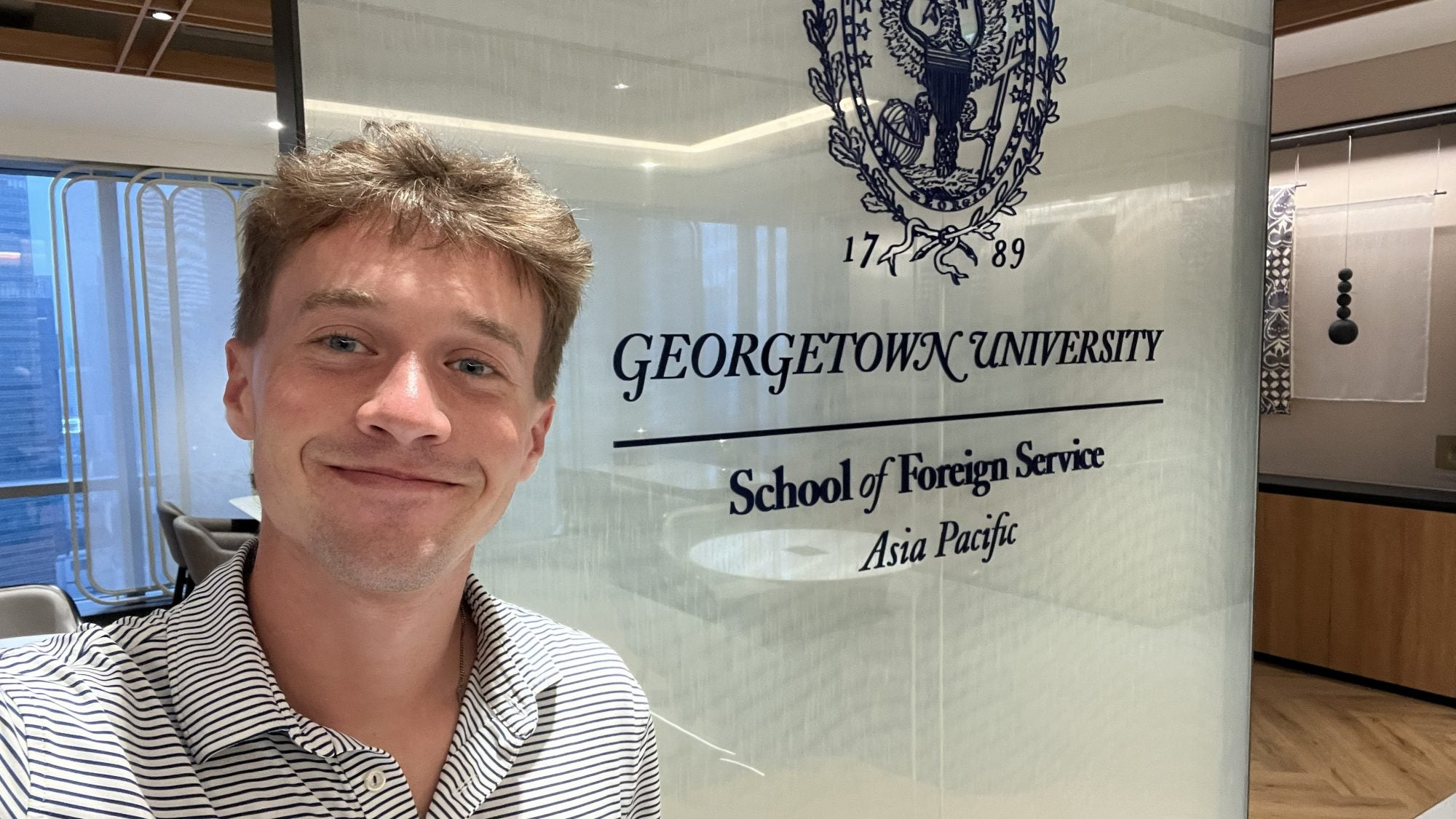 Young man smiling in a GU polo shirt