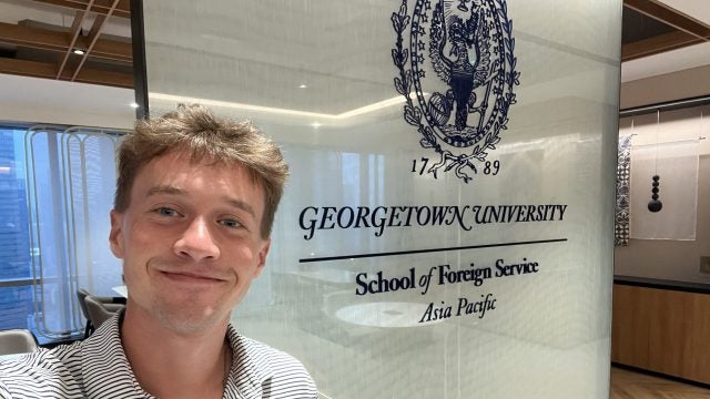 Young man smiling in a GU polo shirt
