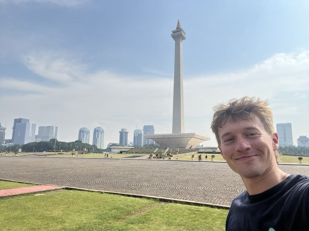 Young man selfie in front of a tall tower in a sunny day