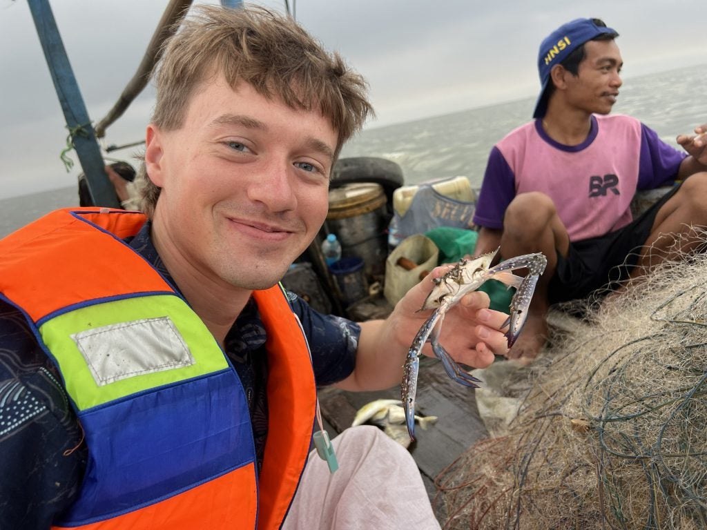 Young man holding a crab while wearing life vest