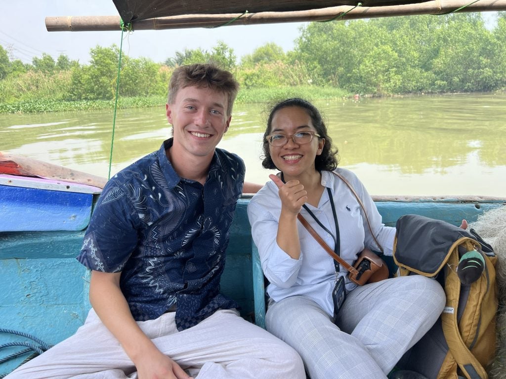 Young man and a woman sitting on a boat smiiling