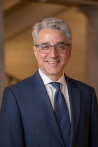 Man in a suit wearing glasses and smiling