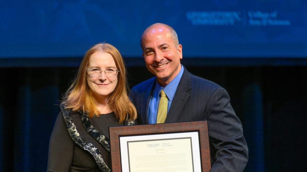 Woman and man on stage holding an award