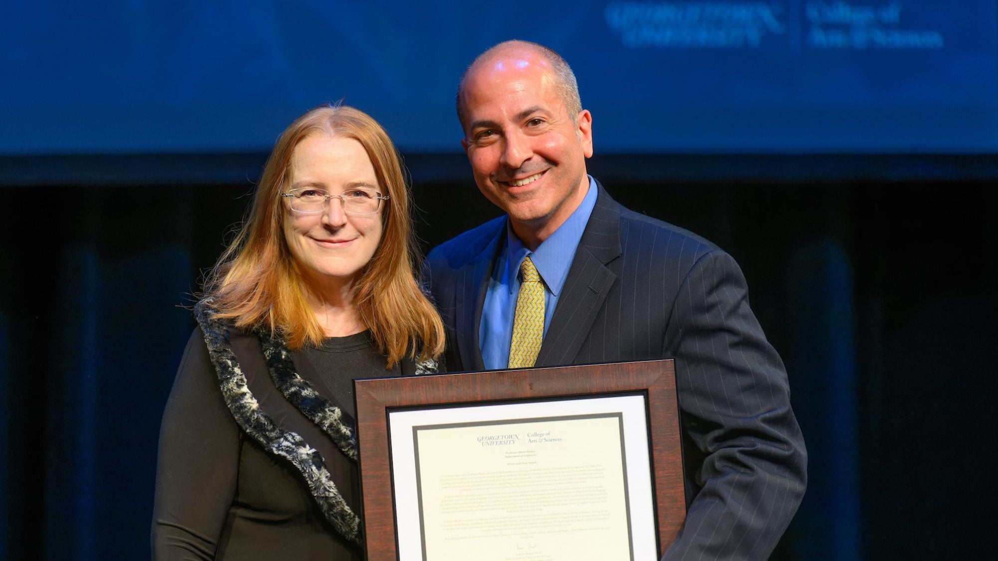 Woman and man on stage holding an award
