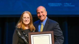 Woman and man on stage holding an award