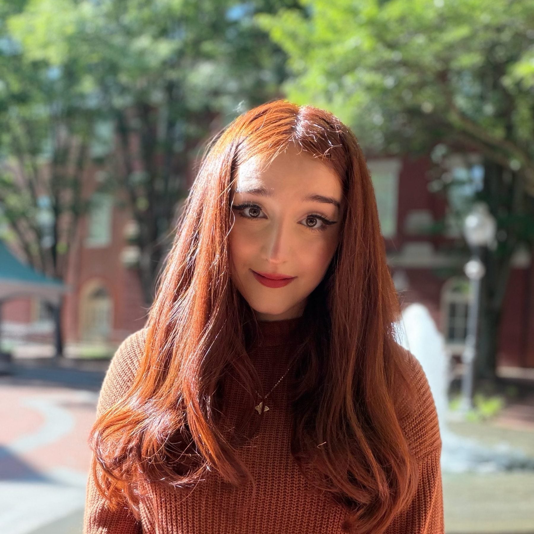 Young woman with red hair standing in sun
