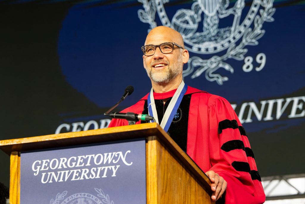 Man with glasses in red graduation regalia