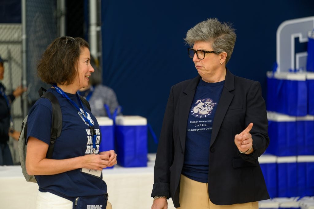 Woman in a blazer with glasses talking with another woman