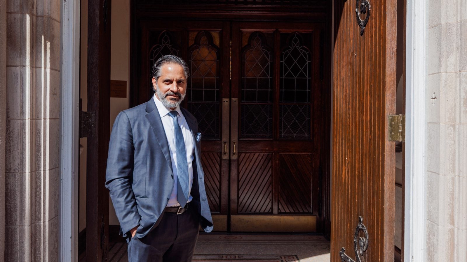 Georgetown President Eduardo Peñalver stands in front of a chapel entrance in a suit