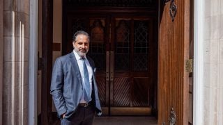 Georgetown President Eduardo Peñalver stands in front of a chapel entrance in a suit